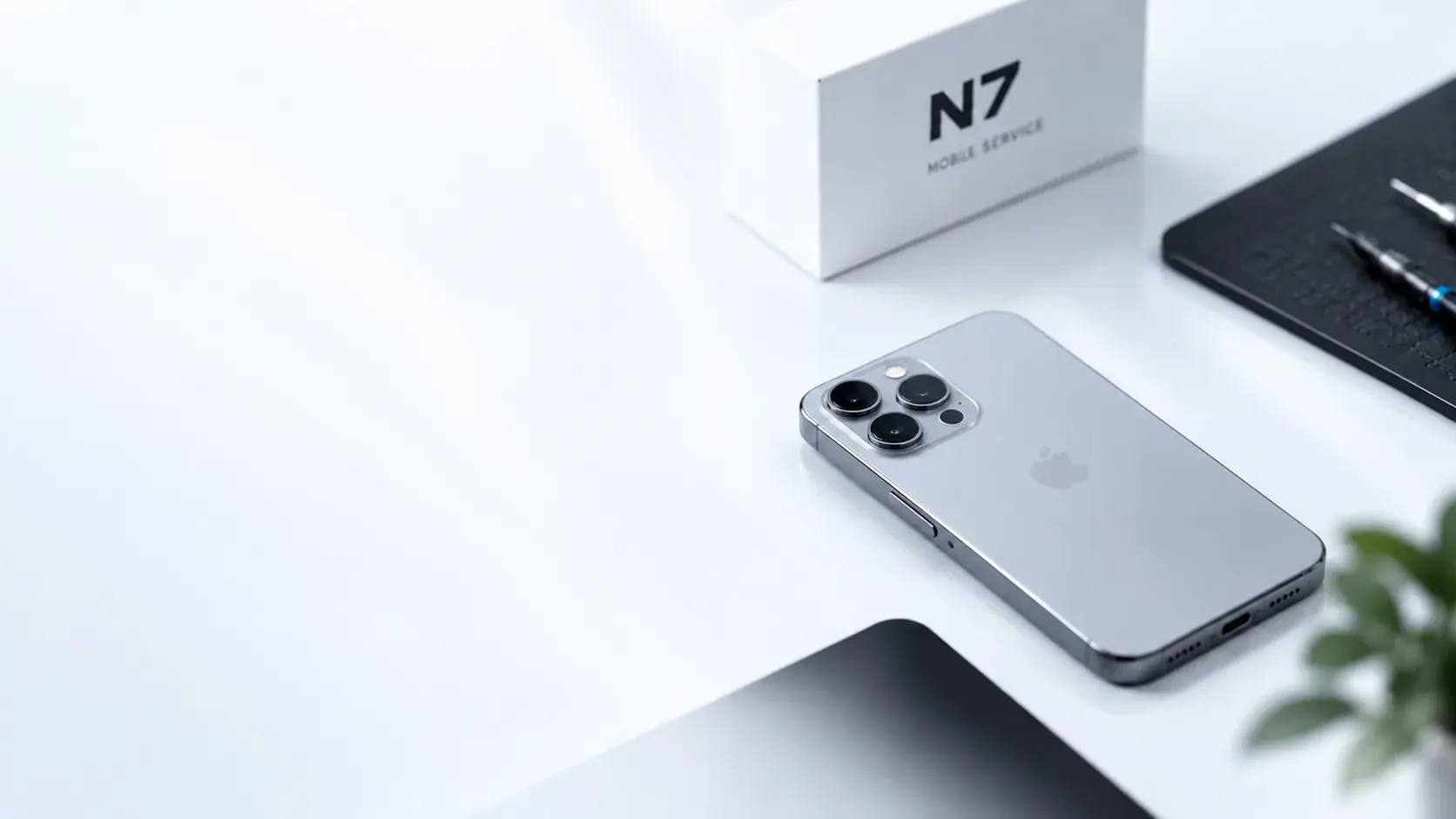 Renoverad iPhone på ett vitt skrivbord bredvid en N7-ask